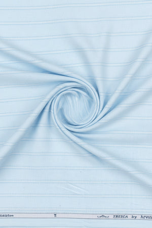 Close-up of light blue fabric with a subtle pattern, featuring the brand 'Arvind Tresca' at the bottom.