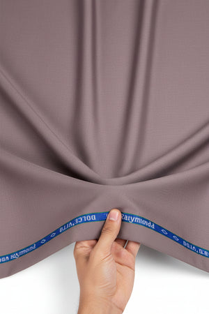A close-up of a dusty mauve or muted mauve fabric texture, with a blue branded tape strip visible along the top edge reading 'Dolce Vita by Reynolds'.