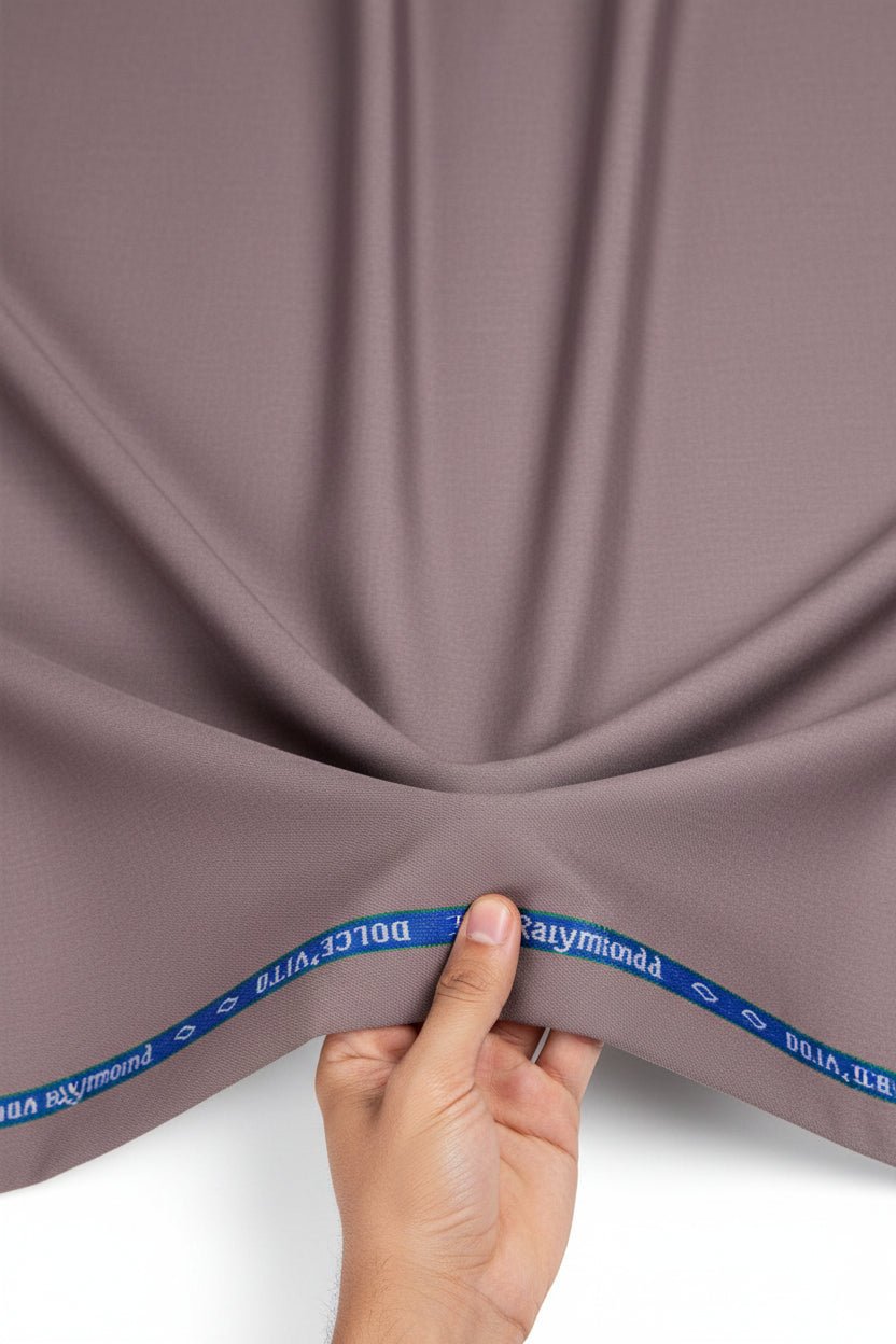 A close-up of a dusty mauve or muted mauve fabric texture, with a blue branded tape strip visible along the top edge reading 'Dolce Vita by Reynolds'.